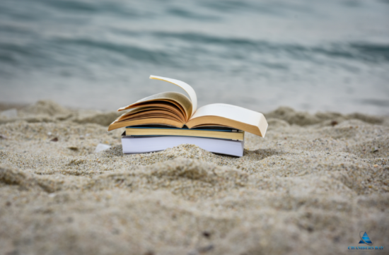 Reading books stacked on a beach